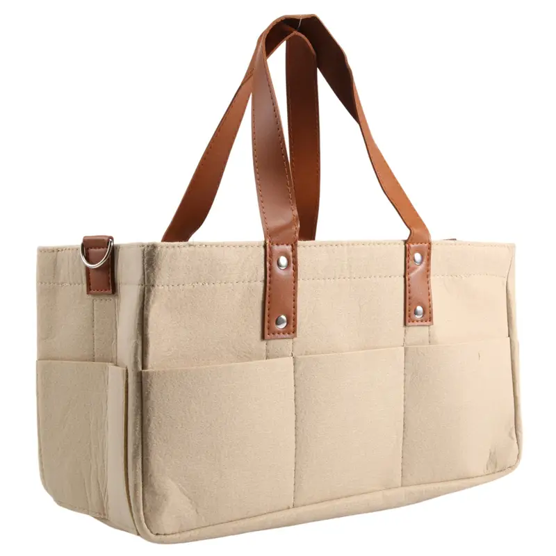 Beige canvas felt baby diaper caddy nursery storage basket with brown leather handles and trim.