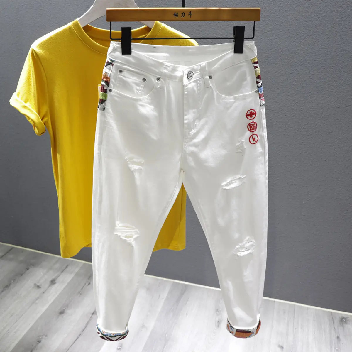 men slim fit stretch embroidered white denim jeans featuring colorful embroidered patches and red circular logos on the side.