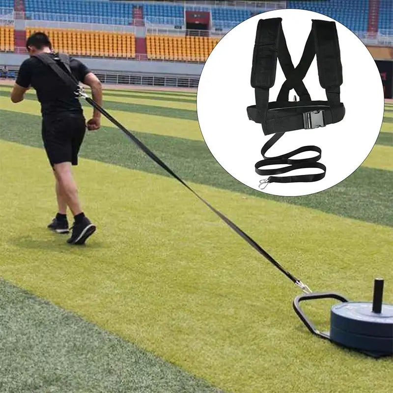 Black resistance training harness with adjustable straps and metal buckle connected to a weighted sled for athletic conditioning in the agility training resistance harness sled pull strap.