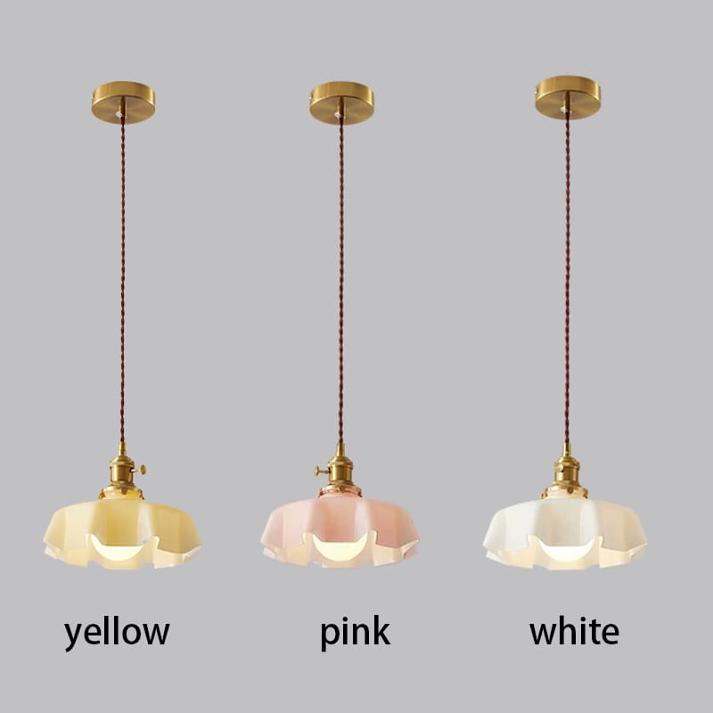 Trois luminaires suspendus avec des supports de tête de lampe en cuivre en métal à finition dorée et des cordons en tissu, présentant des abat-jours en verre translucide en forme de jupe florale dans des tons jaune, rose et blanc, vus depuis l’avant.