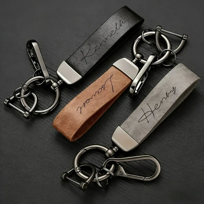 Three personalized custom engraved leather keychains with black tan and gray straps featuring silver toned metal hardware for a personalized gift.