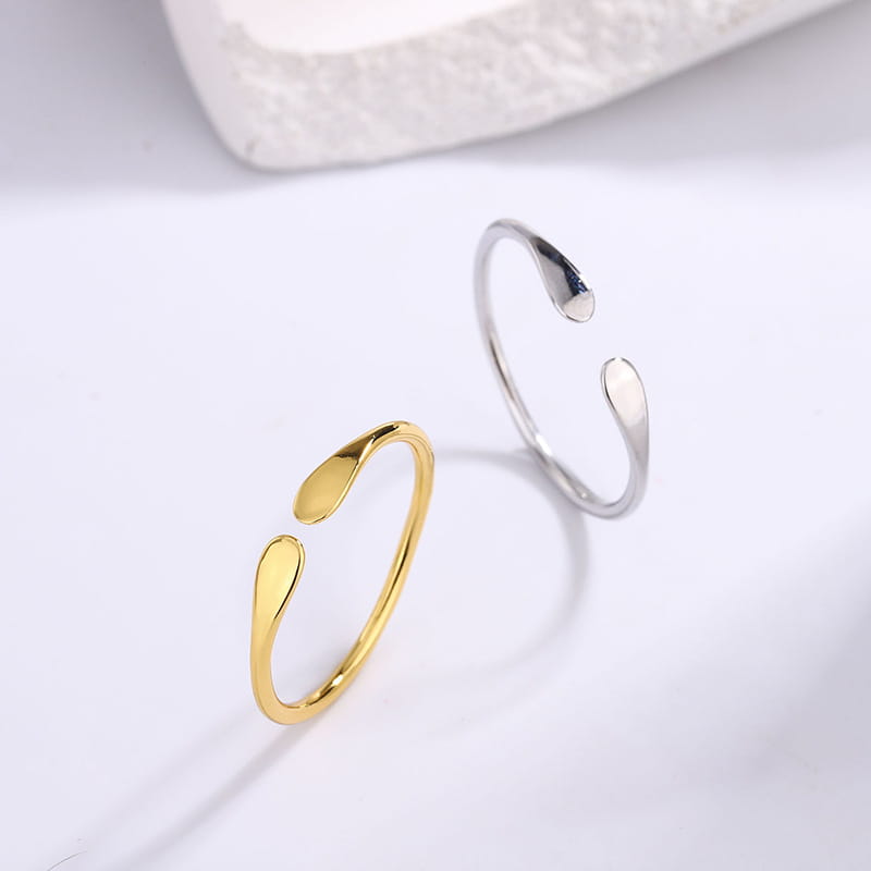 Dos anillos apilables minimalistas abiertos de plata de ley, en oro y plata respectivamente, cada uno con un diseño elegante con forma de gota.