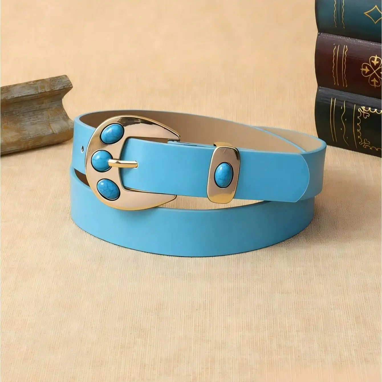 Ein hellblaues Lederarmband (Gürtel) mit türkisfarbenem Leder, einer goldfarbenen Schnalle, verziert mit drei türkisfarbenen Steinen sowie passenden türkisfarbenen Einlagen am Halter.