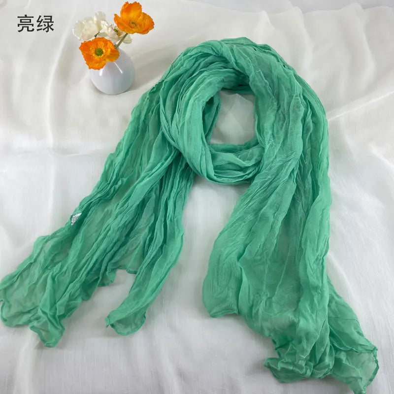 Écharpe en coton et lin plissé vert vif, légère et fluide, avec une texture souple et fluide.