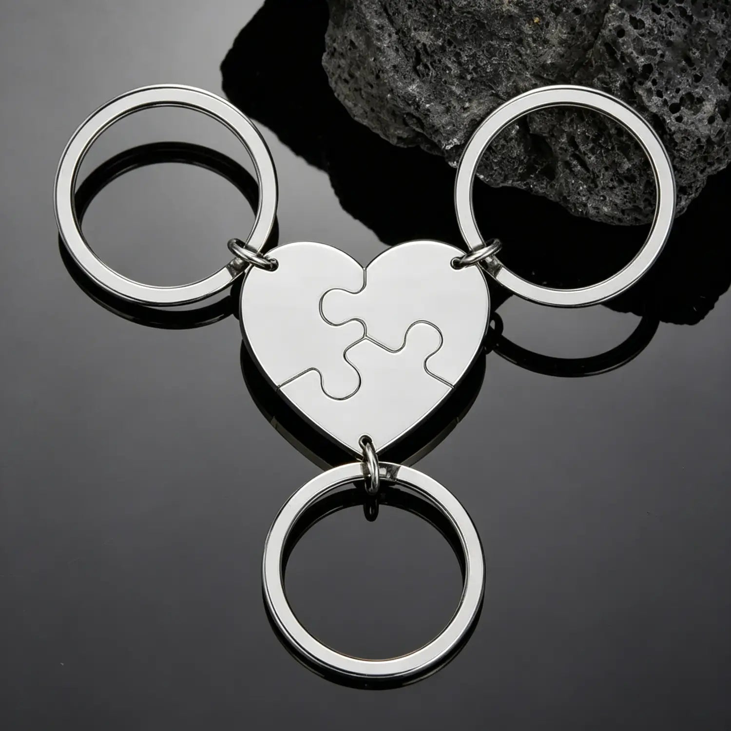 Silver heart-shaped keychain made of metal with a puzzle-piece design and three interlocking rings for custom family use.
