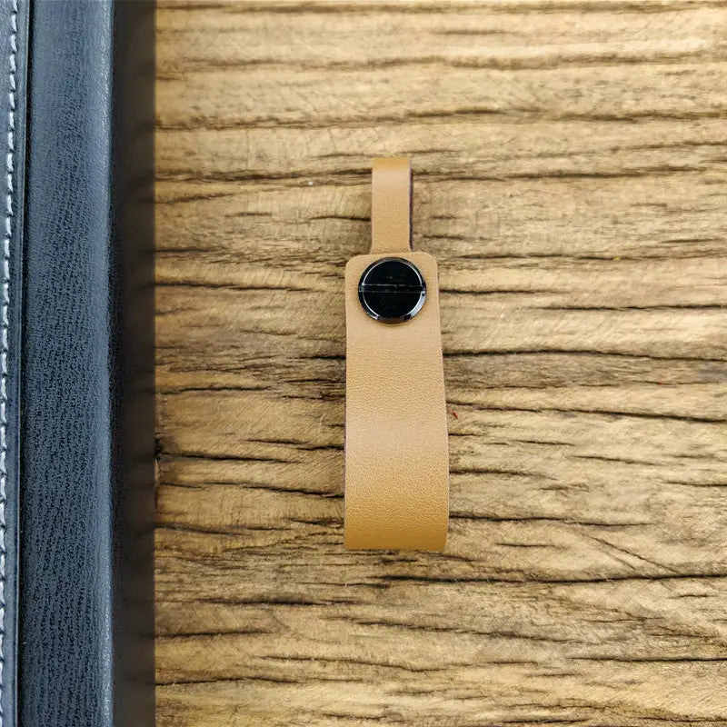 Tan leather strap with a black circular button on the genuine leather car keychain and metal key ring set.