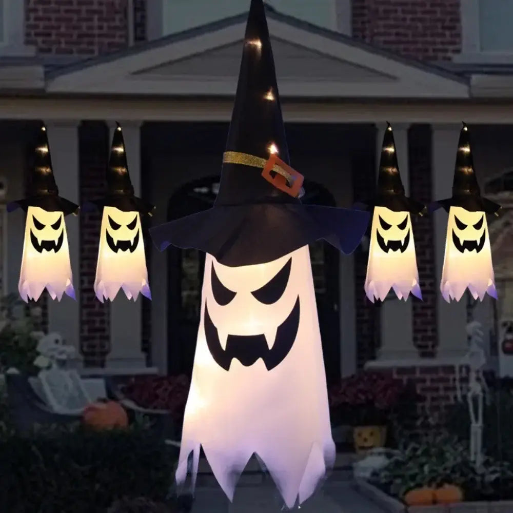 Décoration d’Halloween suspendue à DEL en forme de fantôme gonflable lumineux blanc, avec un visage menaçant portant un chapeau de sorcière noir avec une bande dorée et une boucle orange.