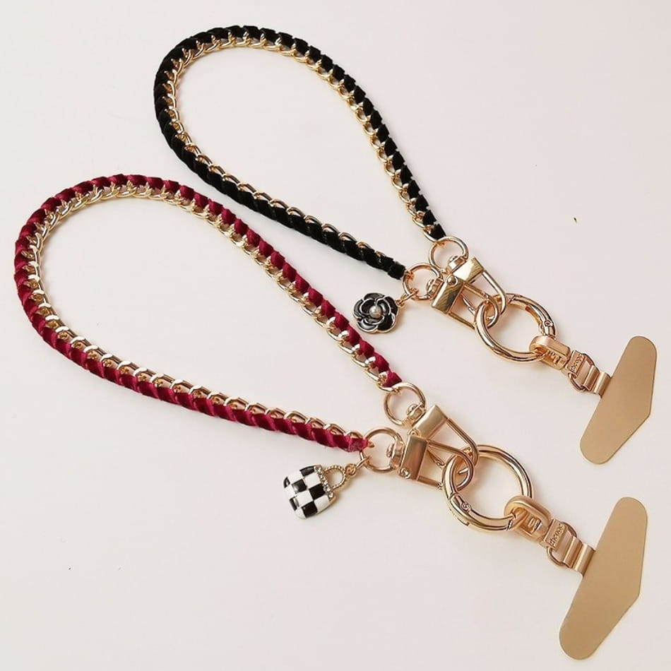 Handy-Handgelenkriemen aus goldfarbener Kette als Anti-Lost-Handylanyard, mit goldfarbenen Kettenriemen, geflochtenen roten und schwarzen Stoffkorden sowie kleinen dekorativen Anhängern.