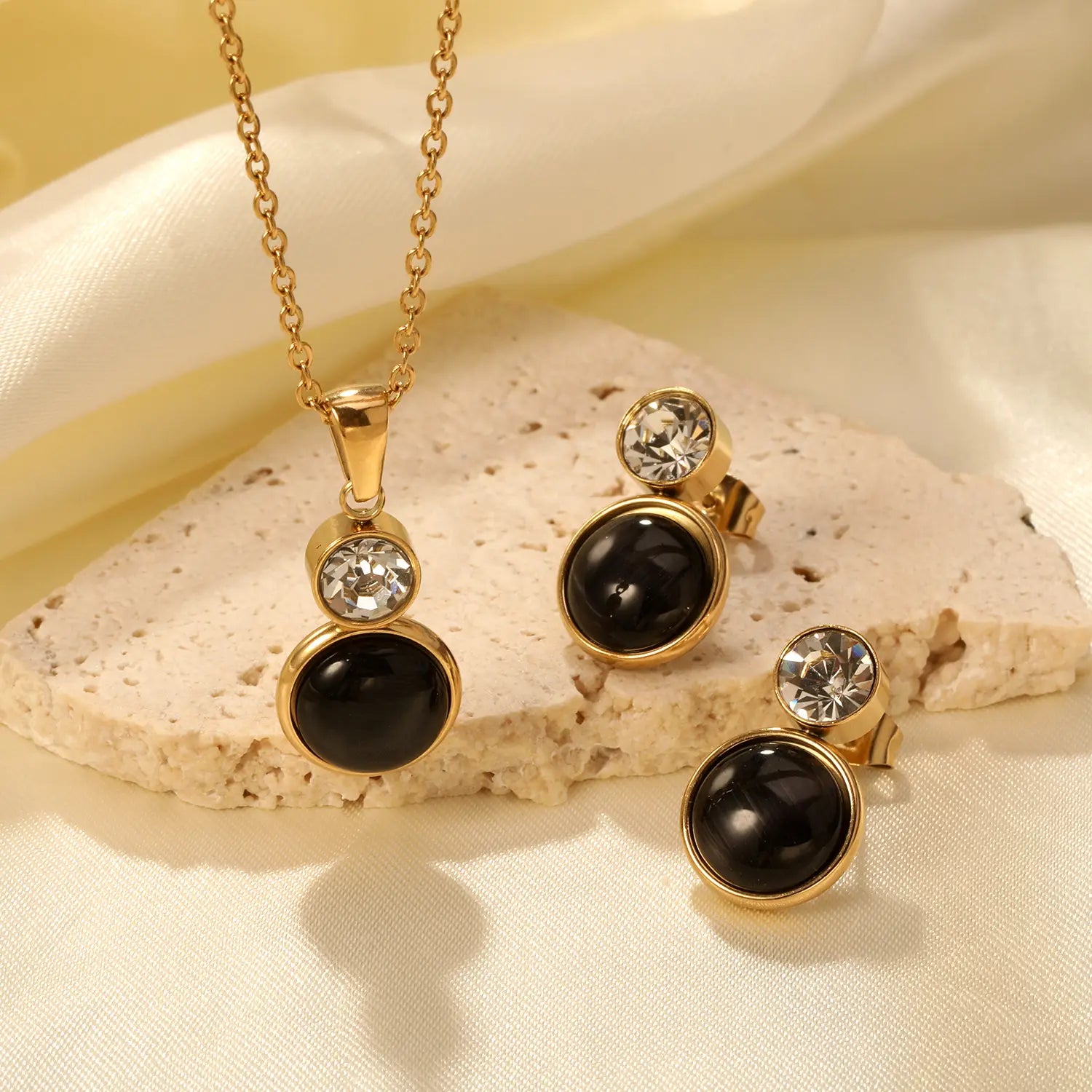 Gold-toned stainless steel black opal necklace and matching stud earrings with black onyx stones and clear crystal accents.