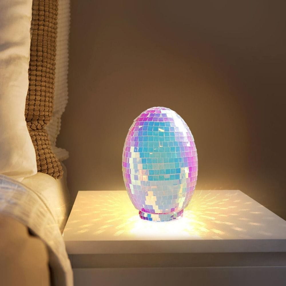 Iridescent glass disco egg ball ornament shaped as a shimmering egg with a mosaic of iridescent tiles reflecting rainbow hues and emitting a warm glow.