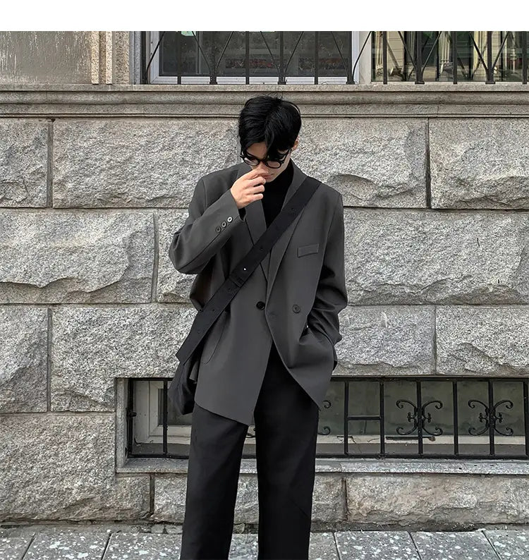 Blazer de doble botonadura casual para hombre en poliéster gris oscuro con ajuste estructurado pero relajado, botones negros y una correa de hombro elegante.