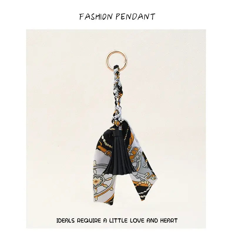 Porte-clés à gland de foulard en soie à motif noir et or pour sacs, avec un gland noir.