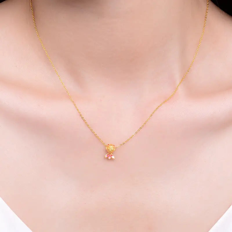 Collier pendentif poisson en or 24 carats délicat, avec des pétales émaillés roses et un centre doré sur une fine chaîne en or.