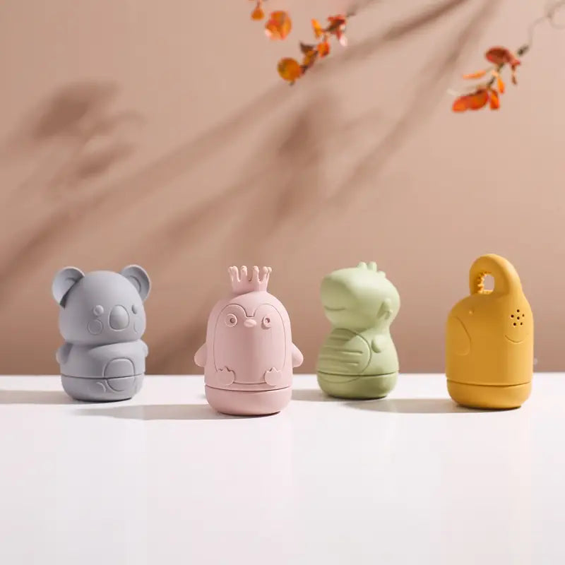 Set aus vier pastellfarbenen Silikon-Koala-Baby-Badesprinkler-Spielzeugen in Grau, Pink, Grün und Gelb, geformt wie Keramik-Tierbehälter.