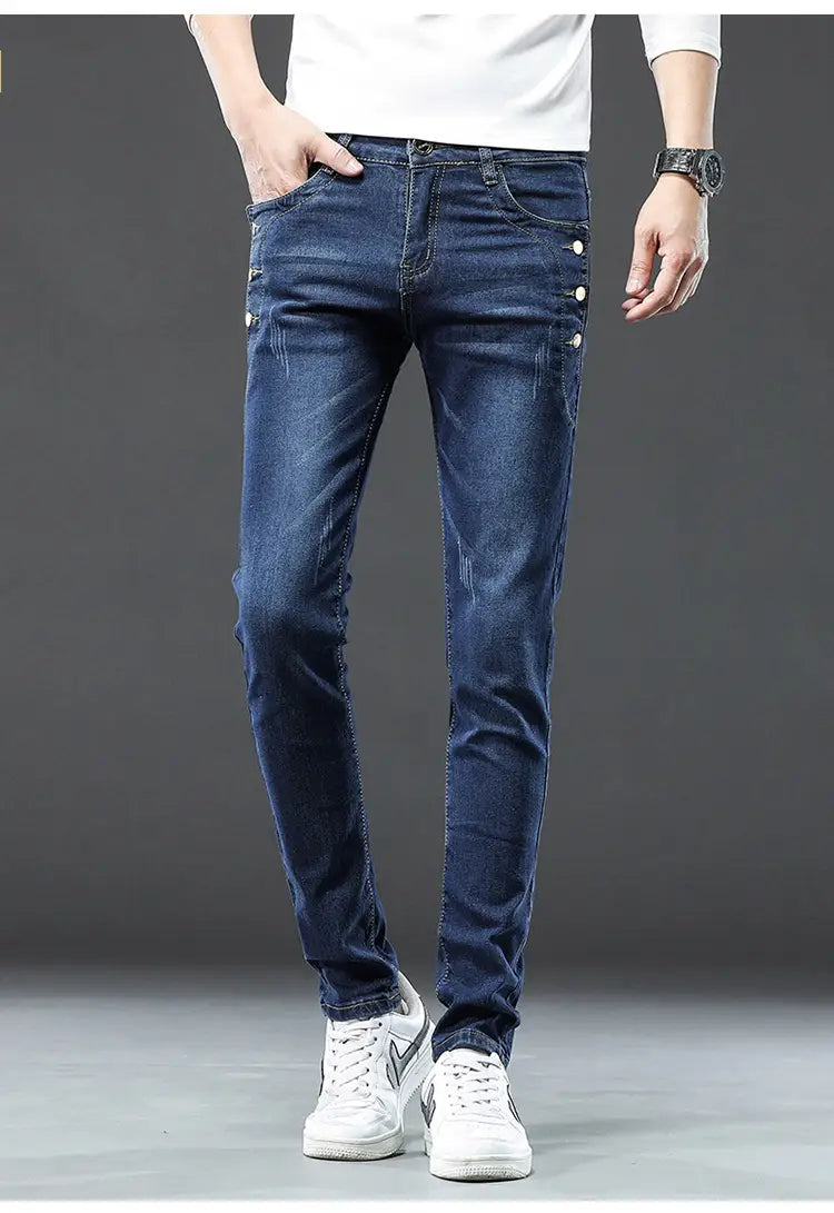 Jeans slim en denim extensible vintage pour hommes, lavage gris, en bleu foncé, coupe slim, avec accents de boutons blancs sur les coutures latérales.