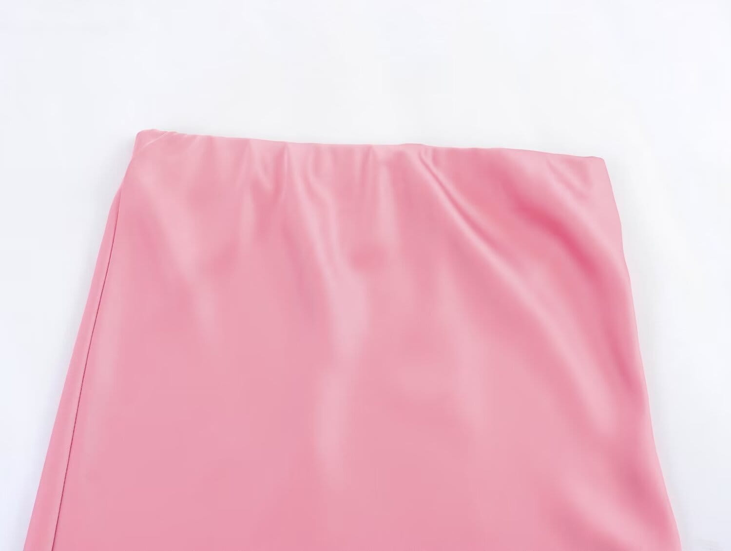 Une jupe midi en satin rose tendre, à taille haute, design long et élégant, surface réfléchissante lisse et plis de tissu subtils.