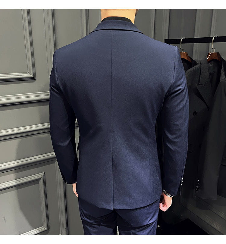 Veste de costume bleu marine, coupée sur mesure, avec un tissage texturé subtil et une fermeture à revers classiques, faisant partie d’un ensemble de costume slim fit pour homme avec 9 pantalons courts à la cheville.