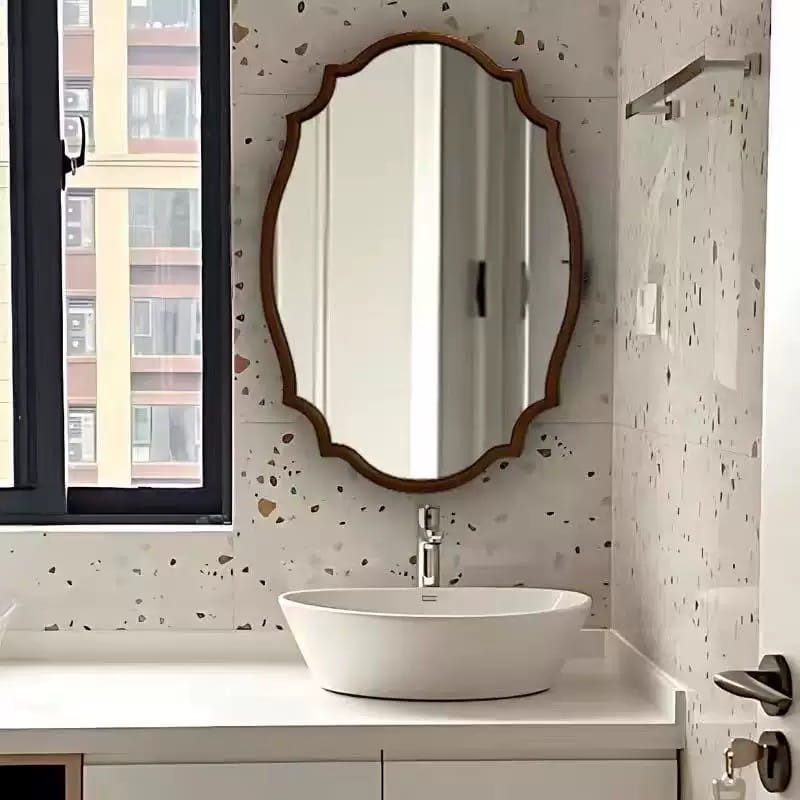 Miroir mural ovale à cadre en bois, doré et ornemental, avec un bord à volutes décoratif, présentant un style de miroir classique pour des miroirs de salle de bains.