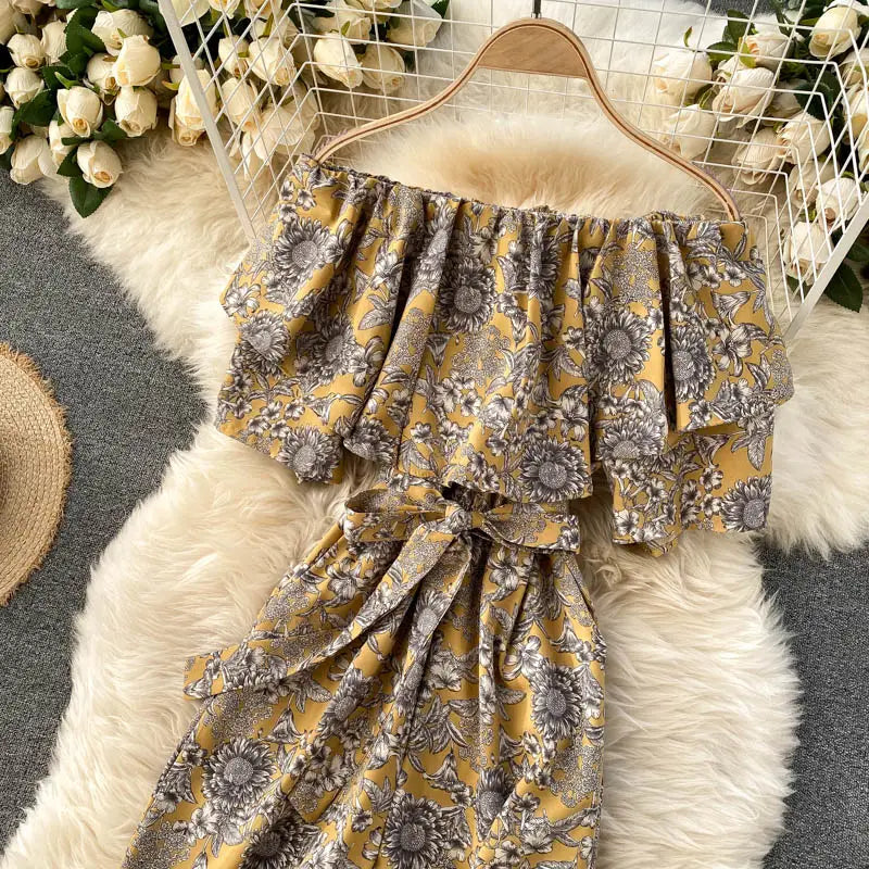 Enterizo de pierna ancha con estampado floral amarillo con escote tipo bardot, mangas con volante con patrón floral gris y cordón en la cintura.