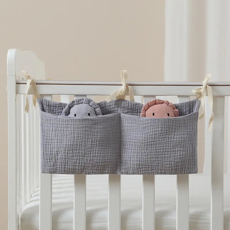 Graue strukturierte Baumwoll-Aufbewahrungstasche für Babybettchen als Organizer neben dem Bett mit zwei Fächern, jeweils mit einem Plüschtier