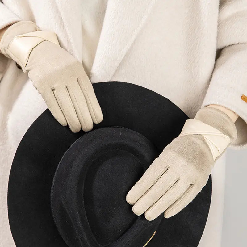 Guantes de invierno para mujer con pantalla táctil de cuero color crema, con acabado suave ligeramente texturizado y correas elegantes para la muñeca, mostrados desde el lado posterior.