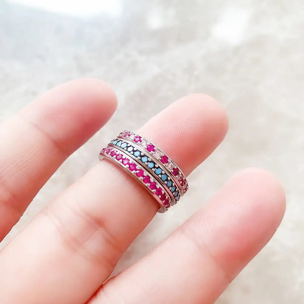 Bague empilée en argent sterling sertie d’une pierre précieuse, comportant un anneau en argent empilé orné de pierres précieuses roses et bleues vibrantes.