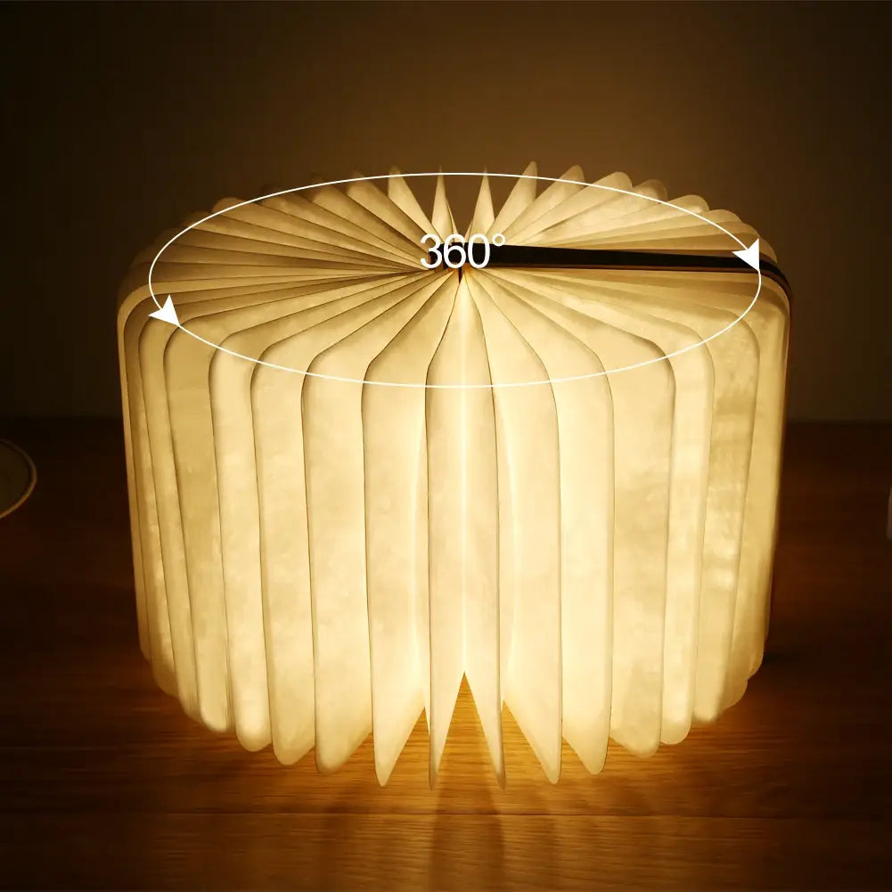 Luz LED plegable con forma de libro que emite un brillo cálido y suave, con apariencia de libro abierto y un diseño tipo acordeón que emite una luz tenue desde su interior.