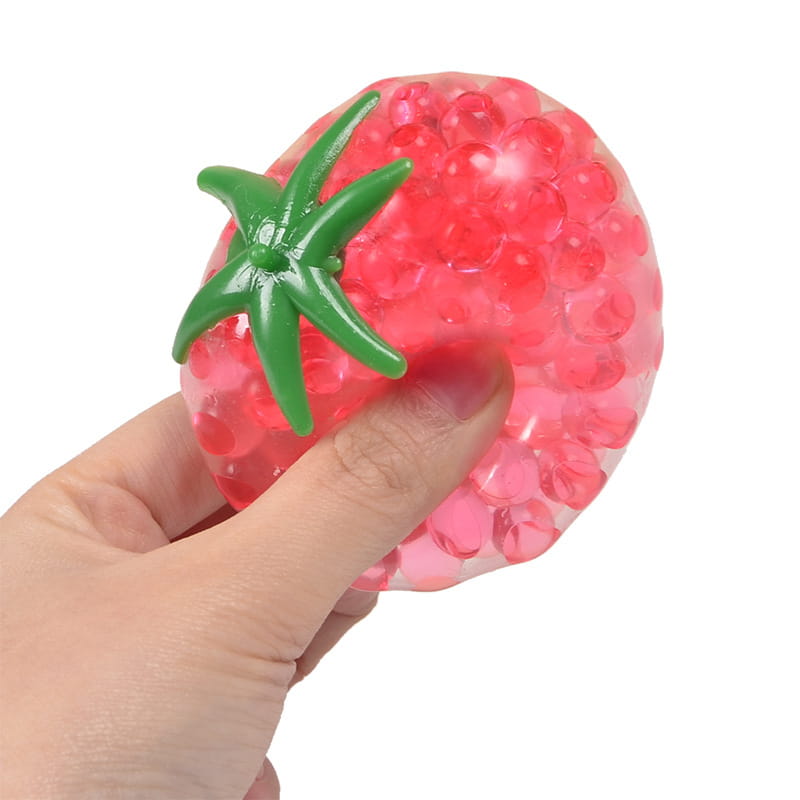 a translucent pink tomato-shaped squishy stress relief toy filled with gel beads and topped with a green plastic stem