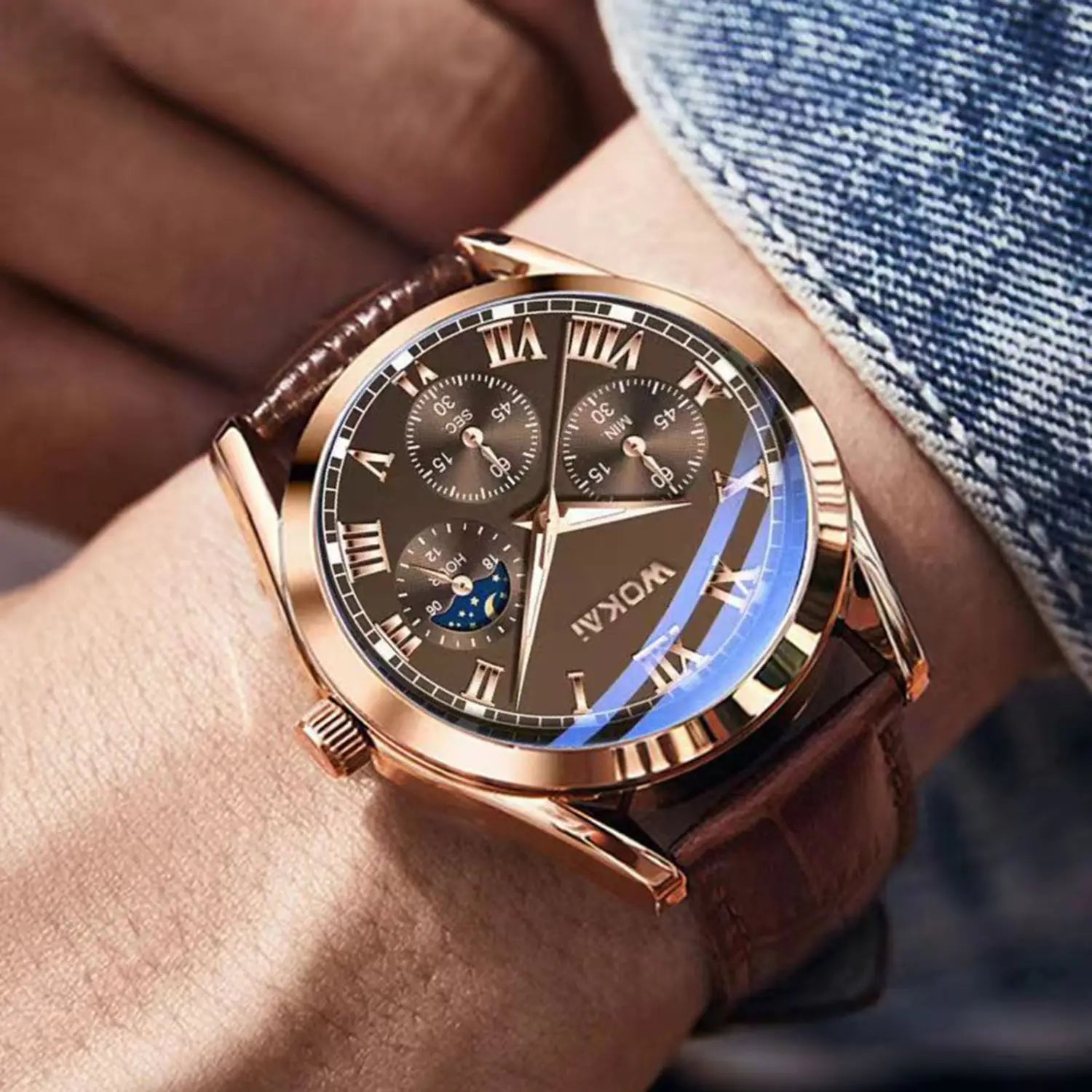 Herren-Quarz-Leder-Geschäftsuhr mit einem roségoldfarbenen Chronographengehäuse von Wokai, dunklem braunem Zifferblatt mit römischen Ziffern, drei Hilfszifferblättern einschließlich einer Mondphasenanzeige sowie einem strukturierten braunen Lederarmband.