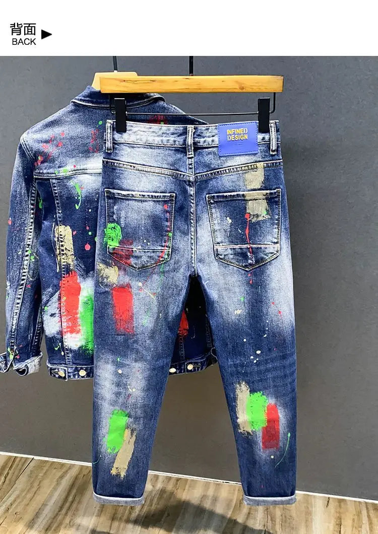 Jeans en denim bleu peints déchirés pour hommes présentant un design d’éclaboussures de peinture colorées accroché à un cintre en bois.