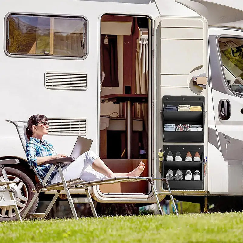 Black foldable shoe storage hanger with multiple compartments mounted on the side of a white camper van designed for rv and wardrobe shoe storage.