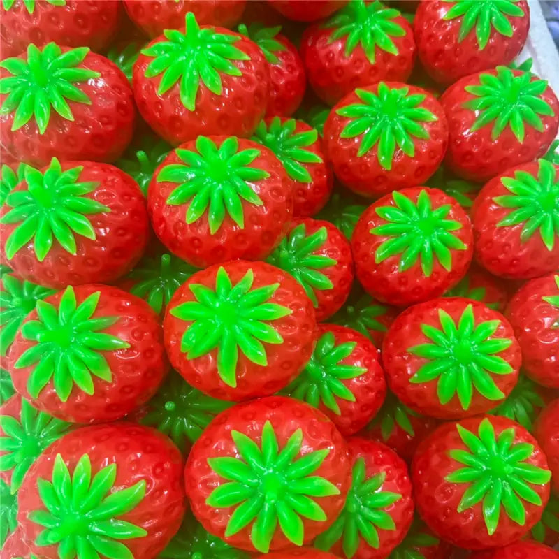 Balles anti-stress en plastique rouges, brillantes et vives, avec des sommets verts feuillus, utilisées comme jouets sensoriels de type balle anti-stress en forme d’arachide