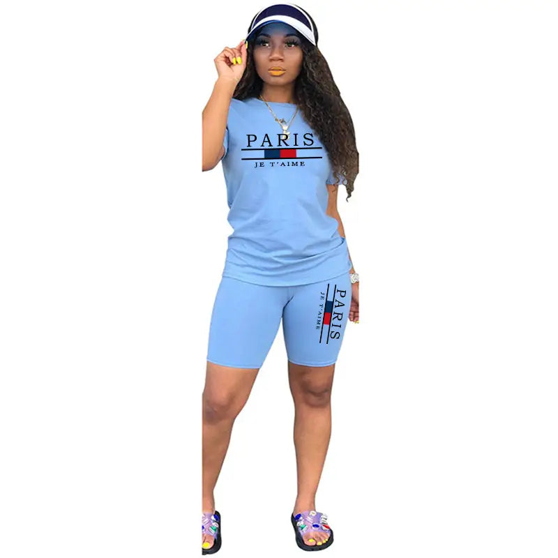 Ensemble deux pièces pour femmes en bleu clair : haut à enfiler avec fermeture et short, comprenant le texte « Paris je t’aime » et un motif de rayures rouge, blanc et bleu sur le haut et les shorts.