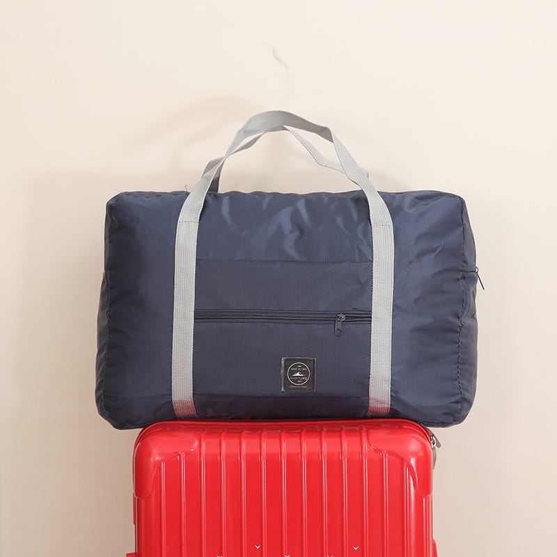 Juego de bolsa de lona de viaje plegable azul marino con asas reforzadas grises y un bolsillo frontal con cremallera.