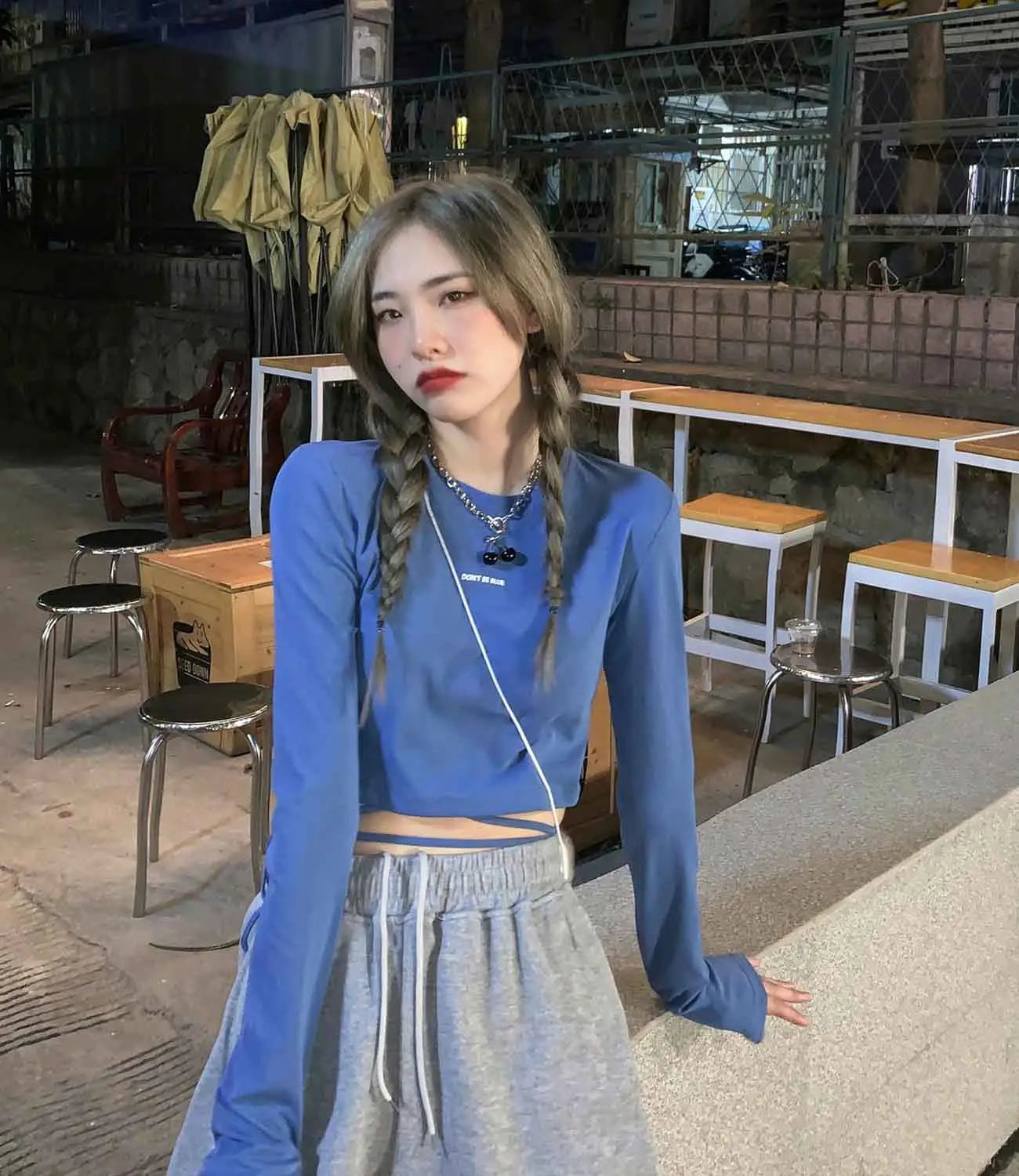 Damen-Langarm-Crisscross-Crop-Top in Blau mit dezentem weißem Logodruck auf der Brust, von vorne abgebildet.