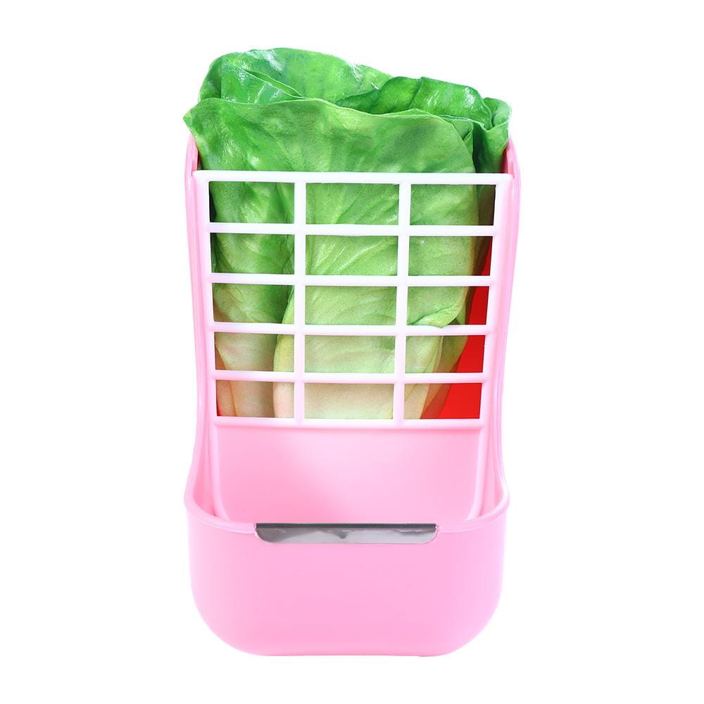 Pink plastic rabbit hay feeder with white grid insert and food bowl holding green lettuce for small animals.