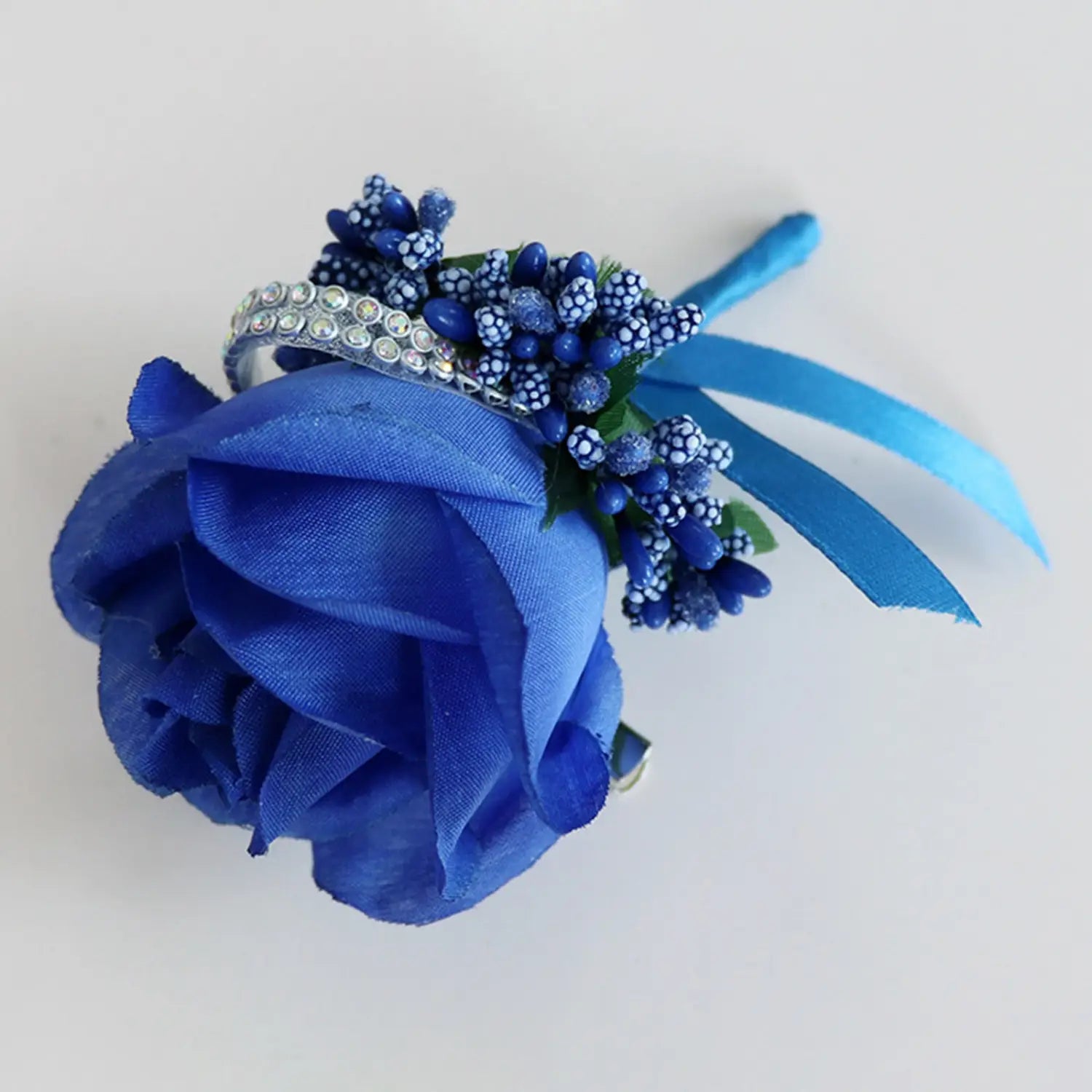 A vibrant royal blue artificial silk rose corsage with sparkling rhinestone accents and delicate matching ribbons for weddings.