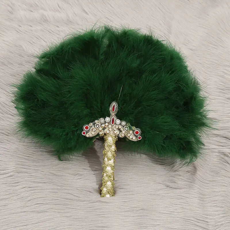 Ein üppiger grüner Feder-Fächer für die Hochzeit als Requisit für den Brauttanz, verziert mit einem funkelnden goldenen Griff und einem kunstvoll verzierten Kopfschmuck mit roten und klaren Edelsteinen.