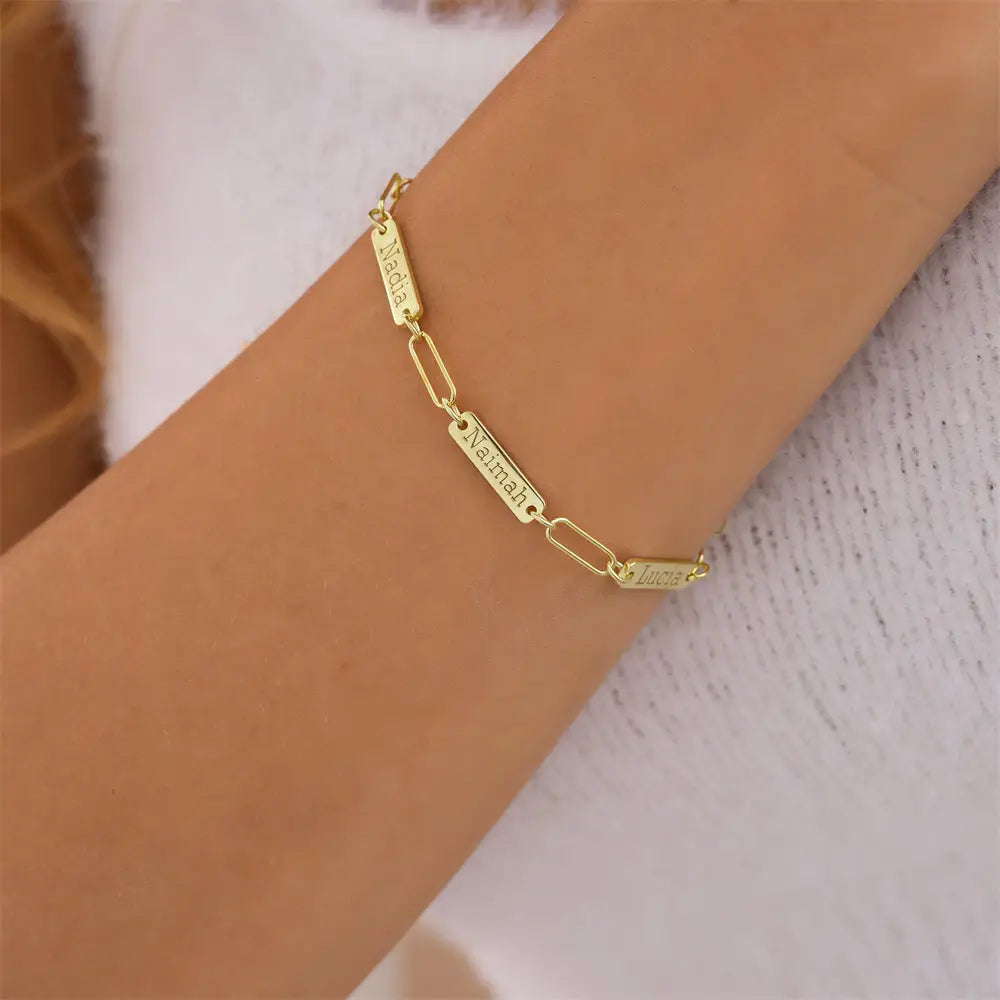 Armband mit goldfarbenem Kettenzubehör und rechteckigen, mit „maddie“, „naimah“ und „luna“ gravierten Namensanhängern, vorgestellt für ein individuell graviertes Lederarmband mit Namensanhänger für Herren.