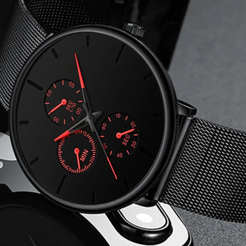 Montre à quartz à maille noire ultrafine pour hommes, avec un cadran chronographe noir, des accents rouges et une sangle en maille.