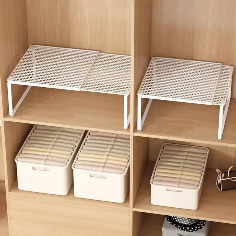étagère d’armoire télescopique empilable en plastique blanc, avec motif en grille et pieds métalliques fins, servant de séparateur d’armoire extensible en métal blanc.
