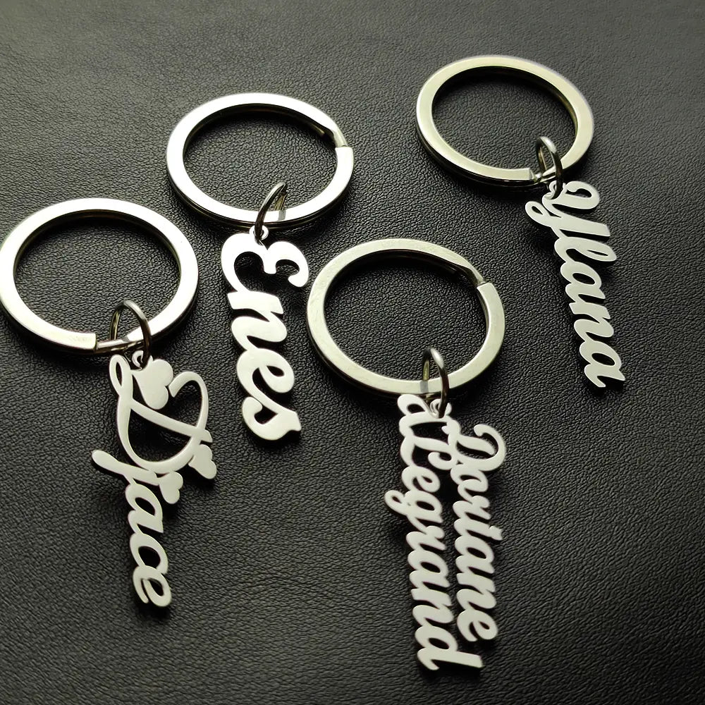 Llavero de nombre personalizado de metal plateado, hecho de joyería de acero inoxidable, con nombres en elegante caligrafía cursiva.