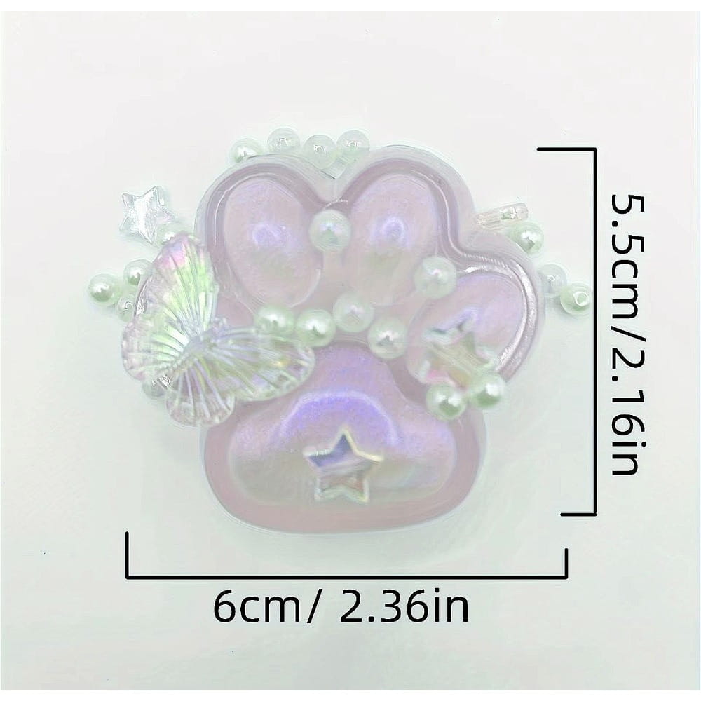 juguete exprimible de pata de gato translúcido con brillo iridiscente en color rosa, elaborado en silicona, que presenta un amuleto con huella de pata adornado con perlas blancas, una mariposa de cristal transparente y adornos con forma de estrellas, diseñado para aliviar el estrés de forma gradual y lenta