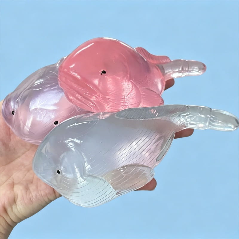 trois balles anti-stress souples en forme de baleine, translucides, rose et plastique transparent, avec des yeux à petits points noirs, provenant du coffret de jouets anti-stress à mâcher « baleine » en matériau souple