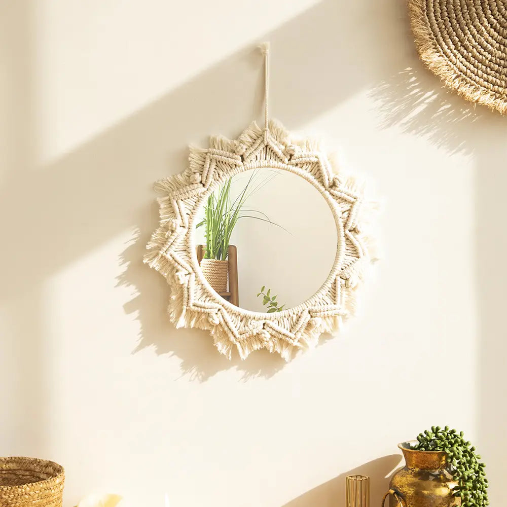 A round cream-colored macrame wall mirror with a sunburst pattern and tassels designed for living room home decor.