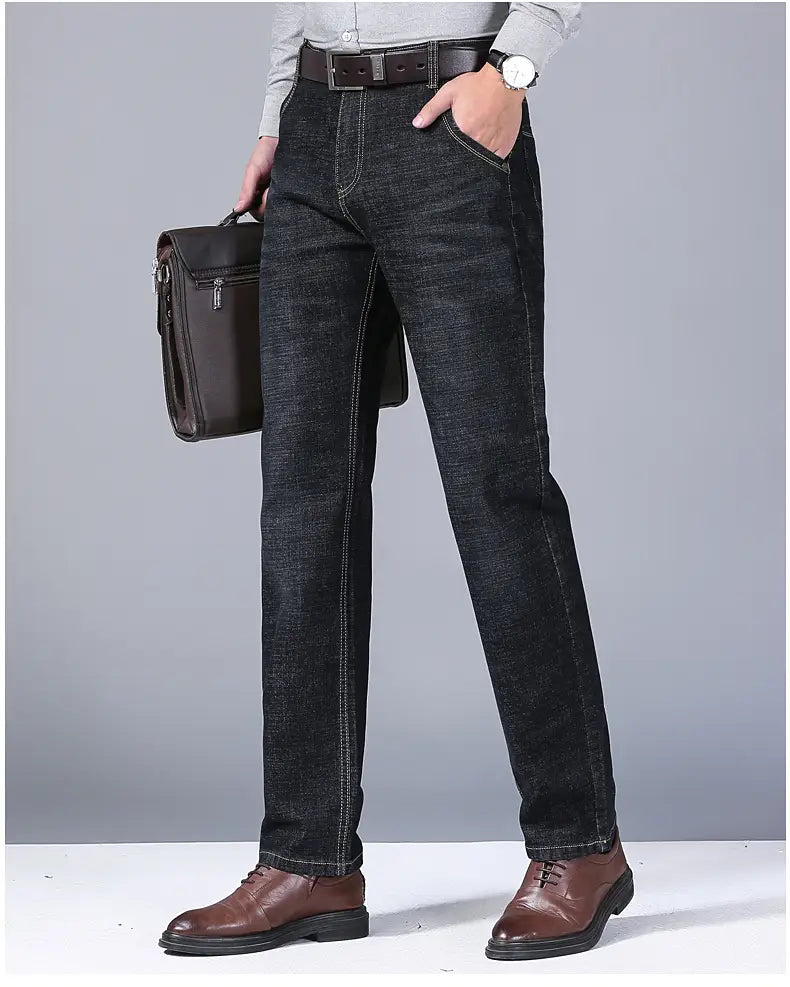 Jeans en denim extensible à coupe slim pour hommes en lavage foncé, avec une coupe droite et des surpiqûres classiques.