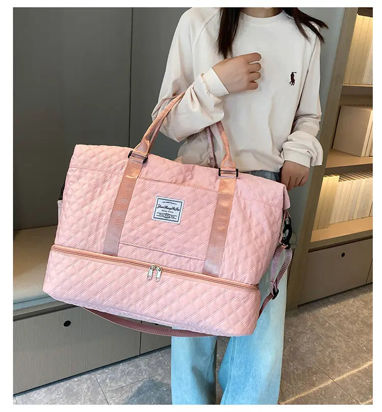 Bolsa de viaje tipo duffel acolchada rosa con asas a juego y bolsillo frontal con cierre, diseñada como un tote weekender grande.