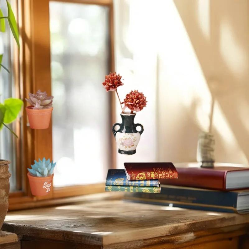 Eine kleine schwarze und weiße Keramikvase mit floralen Mustern und zwei Griffen, die zwei rötlich-orangefarbene Blumen auf einem Miniatur-Holzregal für Puppenhaus-Aufbewahrungsmöbel hält.