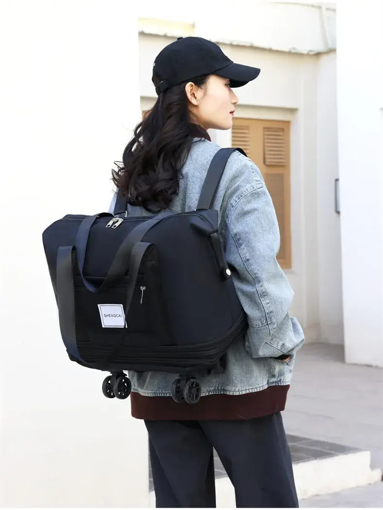Un sac duffel roulant noir à grande capacité, conçu comme sac à dos de voyage, avec des poignées robustes et une petite étiquette blanche à l’avant.