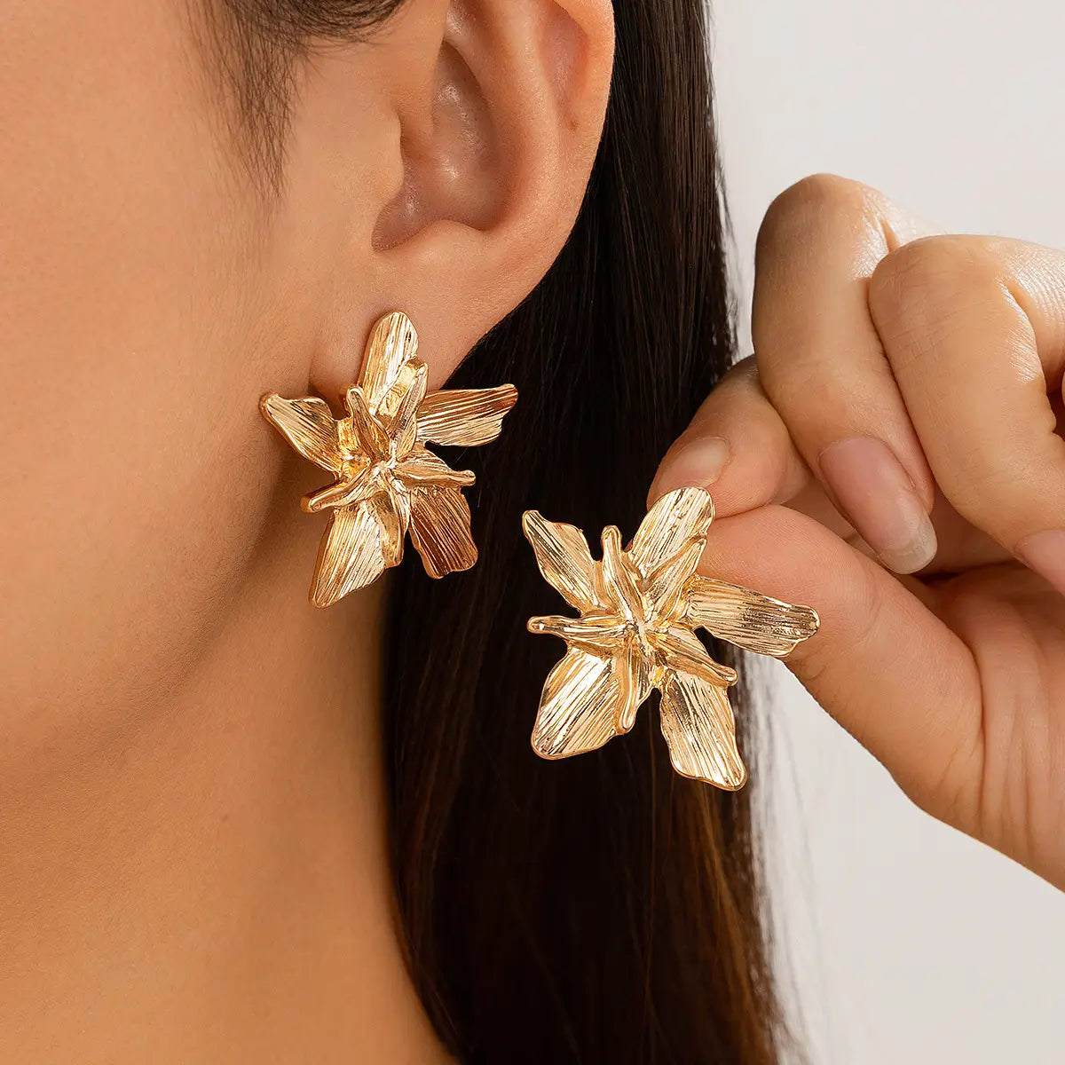Gold-colored flower-shaped earrings with textured petals and a delicate design complement the adjustable double layer flower ring.